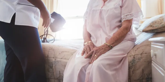 cropped shot of home caregiver with senior woman sitting on bed female doctor visiting her senior patient at home