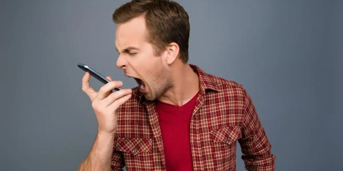 portrait of angry young man screaming on his mobile phone