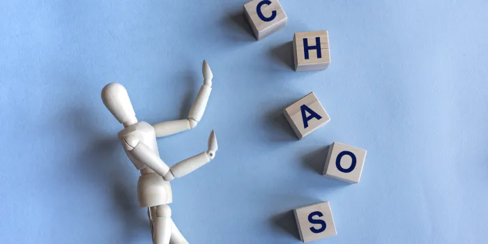 chaos written in wooden cubes and wooden figure on blue background fear of chaos concept