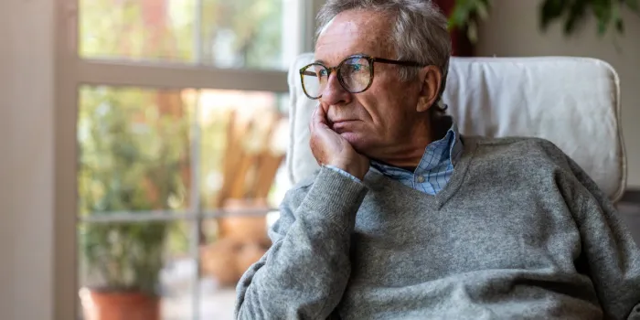senior man looking out of window at home