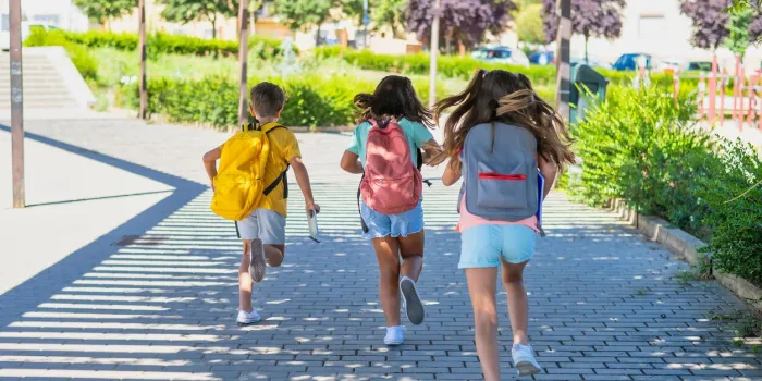 rear view of a group of children running with backpacks on the first day of school 3 classmates back to school education