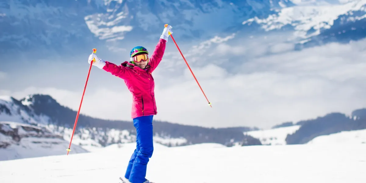 young active woman skiing in mountains female skier kid with safety helmet, goggles and poles enjoying sunny winter day in swiss alps ski race for adults winter and snow sport in alpine resort