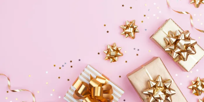 fashion gifts or presents boxes with golden bows and star confetti on pink pastel background top view flat lay composition for birthday, christmas or wedding