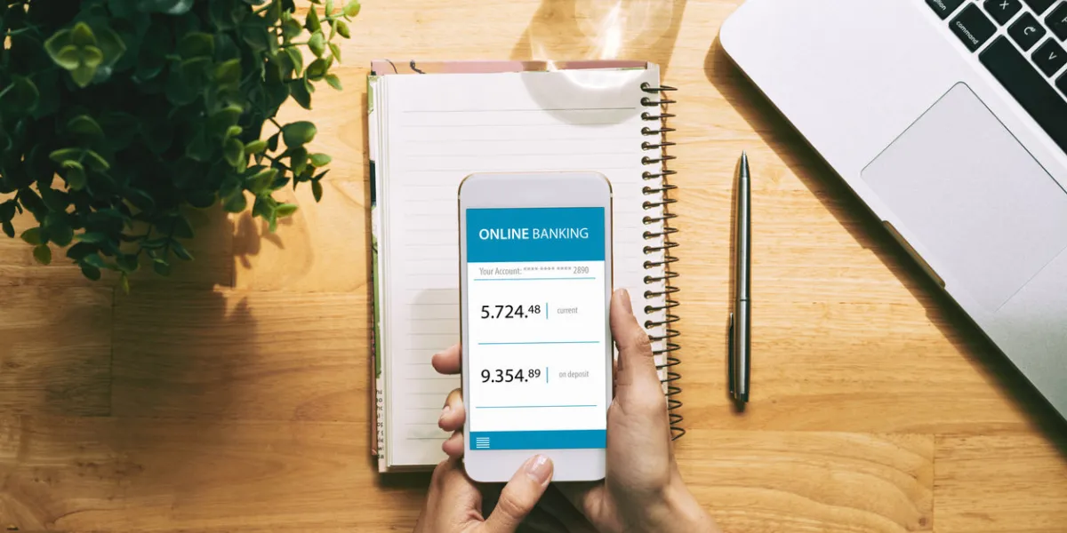 close-up shot of unrecognizable young woman using online banking application on smartphone while sitting at office desk, high angle view