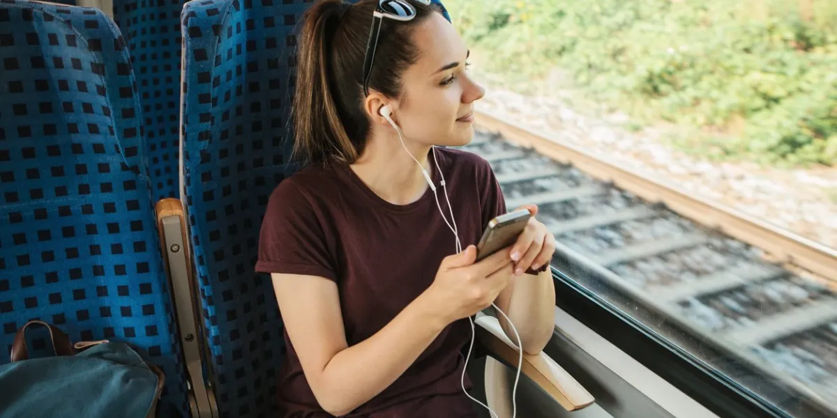 a young girl listens to a music or podcast while traveling in a train