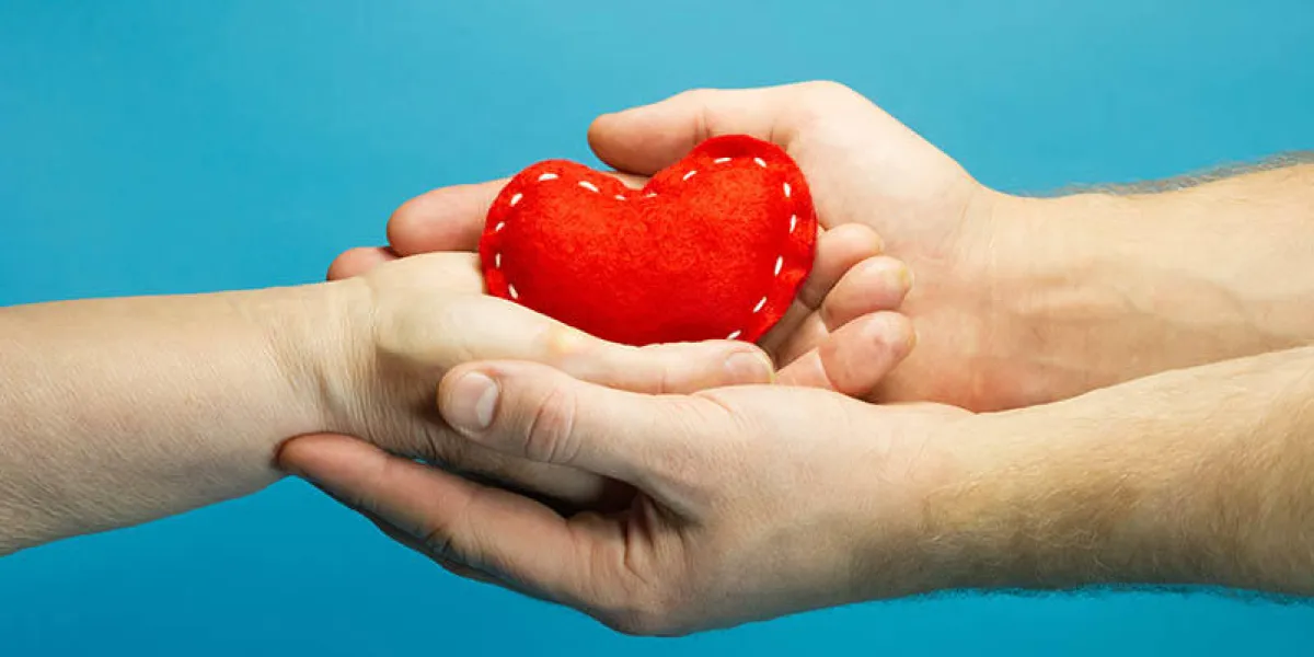 caregiver concept man helping old senior woman hand holding red heart on blue background