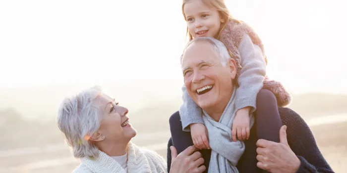 grandparents and granddaughter walking on winter beach laughing