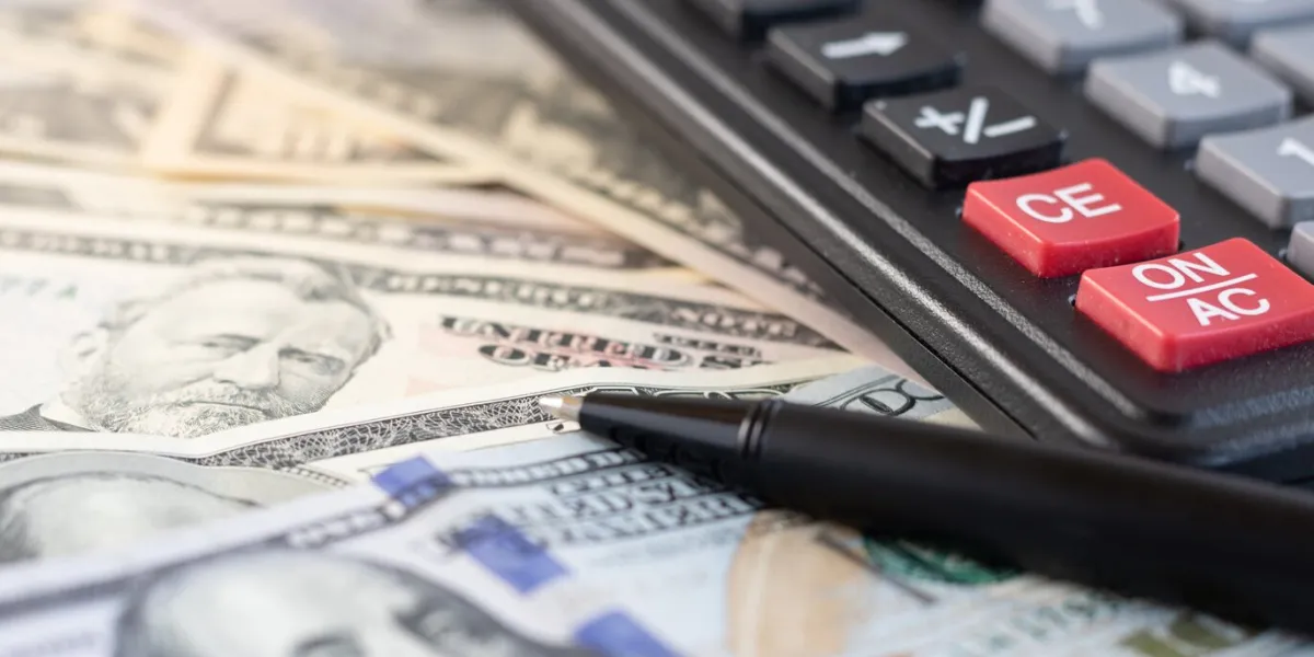 on the table, part of a dollars calculator and pen, closeup