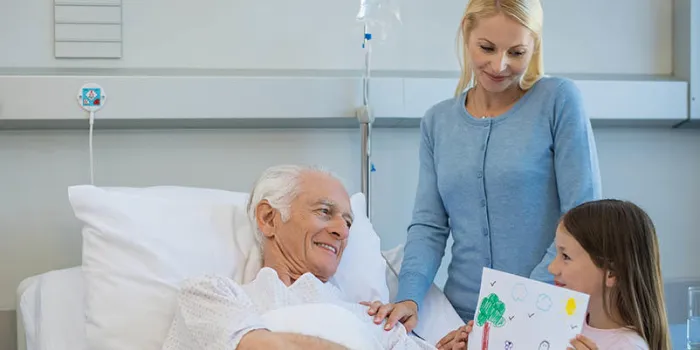 granddaughter showing painting to her old grandfather admitted to hospital senior man feeling excited on seeing painting done by grandchild young woman and little girl visiting ill elderly man in hospital