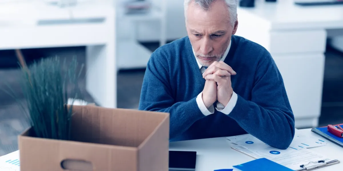 nostalgic mood selective focus on a pensive mature employee thinking about something while sitting at his writing table and working with different printouts at work