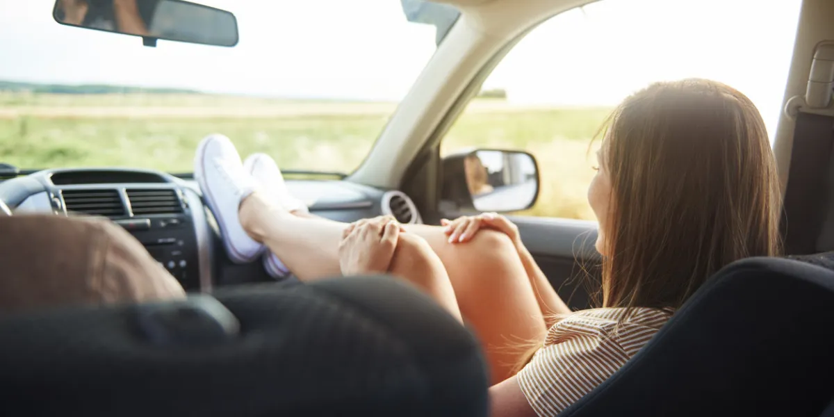 woman holding her legs on dashboard in car