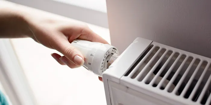 closeup on woman's hand adjusting thermostat valve