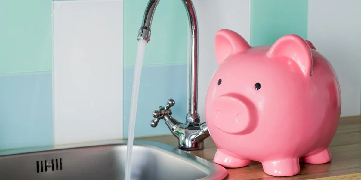 flowing tap water and a piggy bank standing next to it water consumption price concept