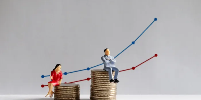 the concept of gender pay gap a miniature man and a miniature woman sitting on top of a pile of coins at different heights in front of a bar graph