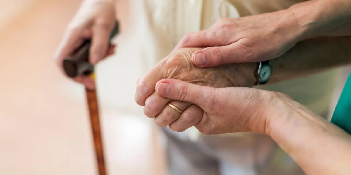 nurse consoling her elderly patient by holding her hands