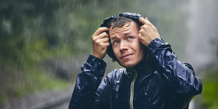 trip in bad weather portrait of young man in drenched jacket in heavy rain