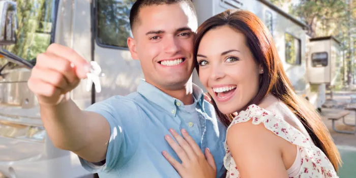 young military couple holding keys in front of new rv