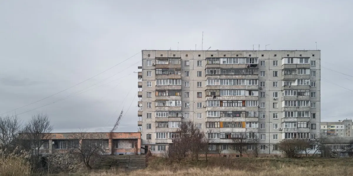 gloomy cloudy cityscape with old gray concrete soviet prefabricated nine-storey panel apartment building