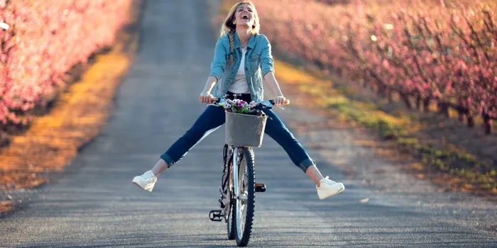shot of pretty young woman with a vintage bike enjoying the time in cherry field in springtime