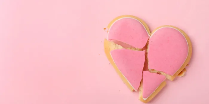 broken heart shaped cookie on pink background, top view with space for text relationship problems concept
