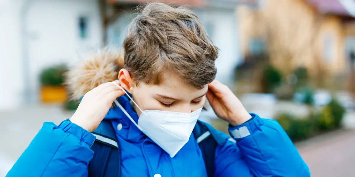 kid boy wearing ffp medical mask on the way to school child backpack satchel schoolkid on cold autumn or winter day with warm clothes lockdown and quarantine time during corona pandemic disease