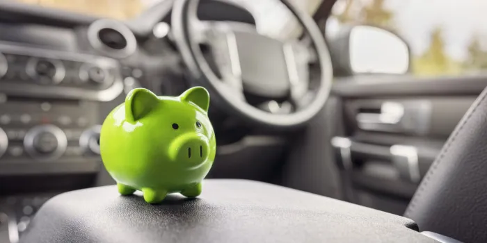 green piggy bank money box in car interior, vehicle purchase, insurance or driving and motoring cost