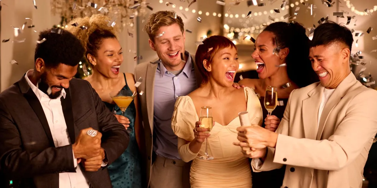 group of friends celebrating at party together with drinks and confetti