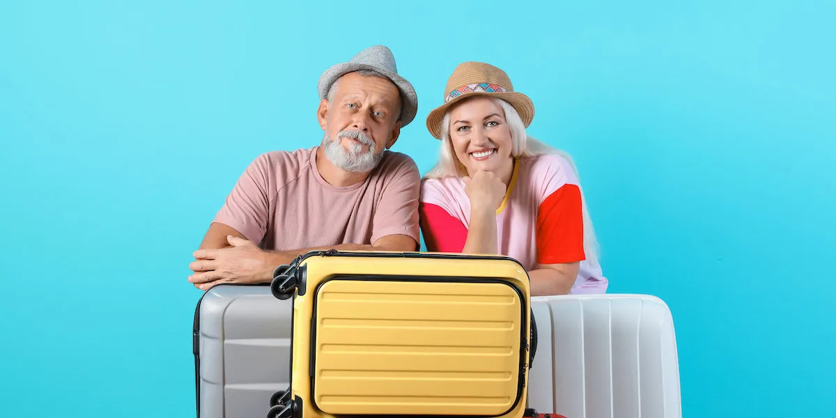 senior couple with suitcases on color background vacation travel