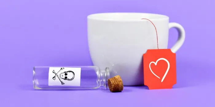 empty open vial with cork and poison skull label next to tea cup with heart on red label on purple background