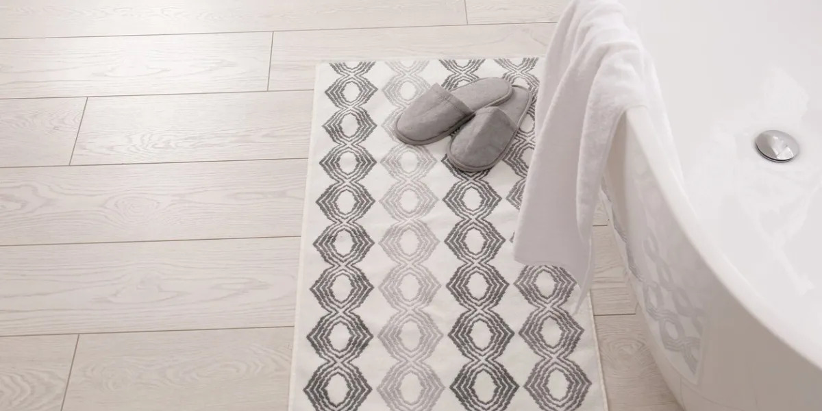 soft bath mat and slippers on floor in bathroom