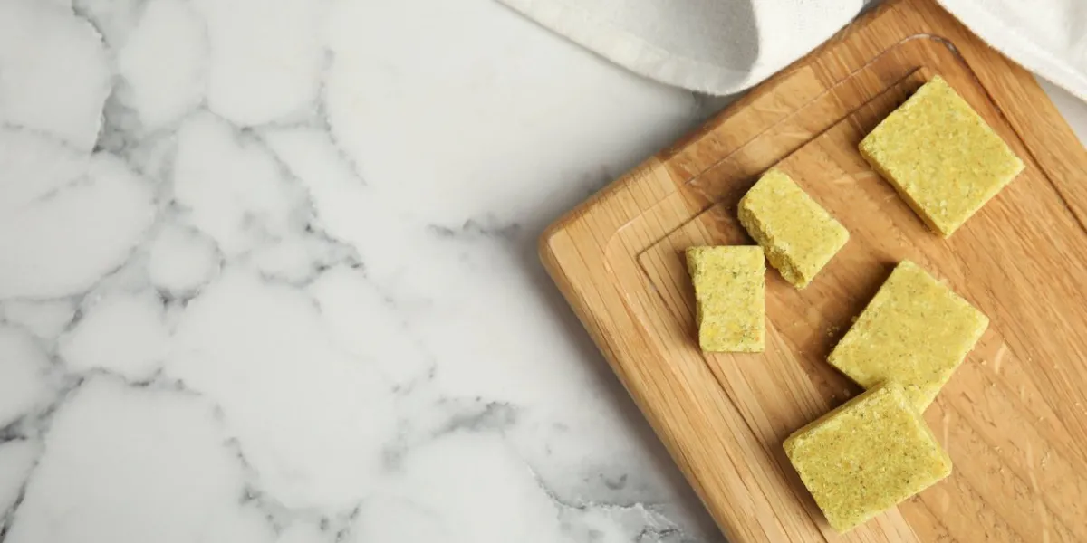 bouillon cubes with wooden board on white marble table, top view space for text