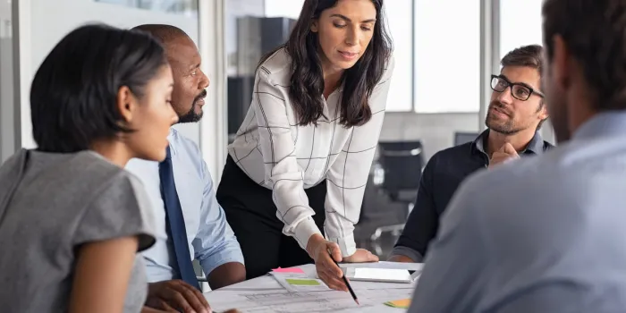 team of multiethnic architects working on construction plans in meeting room engineers and designers discussing project in office businesswoman with business team in conference room working on blueprint