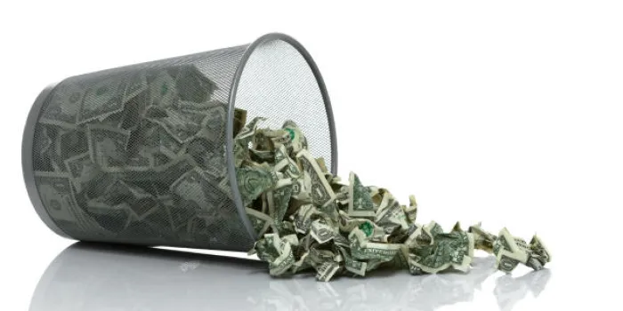 poubelle pleine d'argent inclinée de son côté avec de l'argent débordant