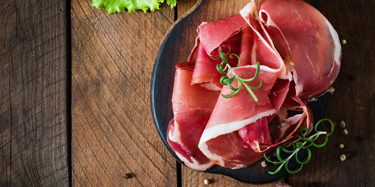 slices of prosciutto on old wooden background