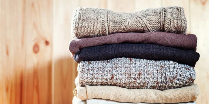 knit cozy sweater folded in a pile on wooden background warm the concept copyspace