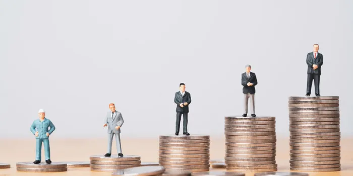 different miniature businessman standing on different height coins stacking , inequality income and salary in each position in company concept