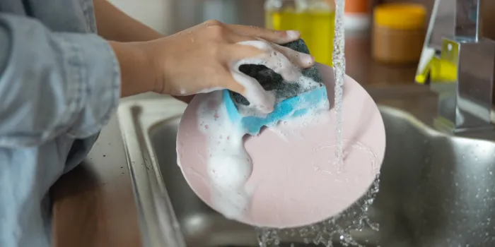 close up of female hands cleaning a dirty plate