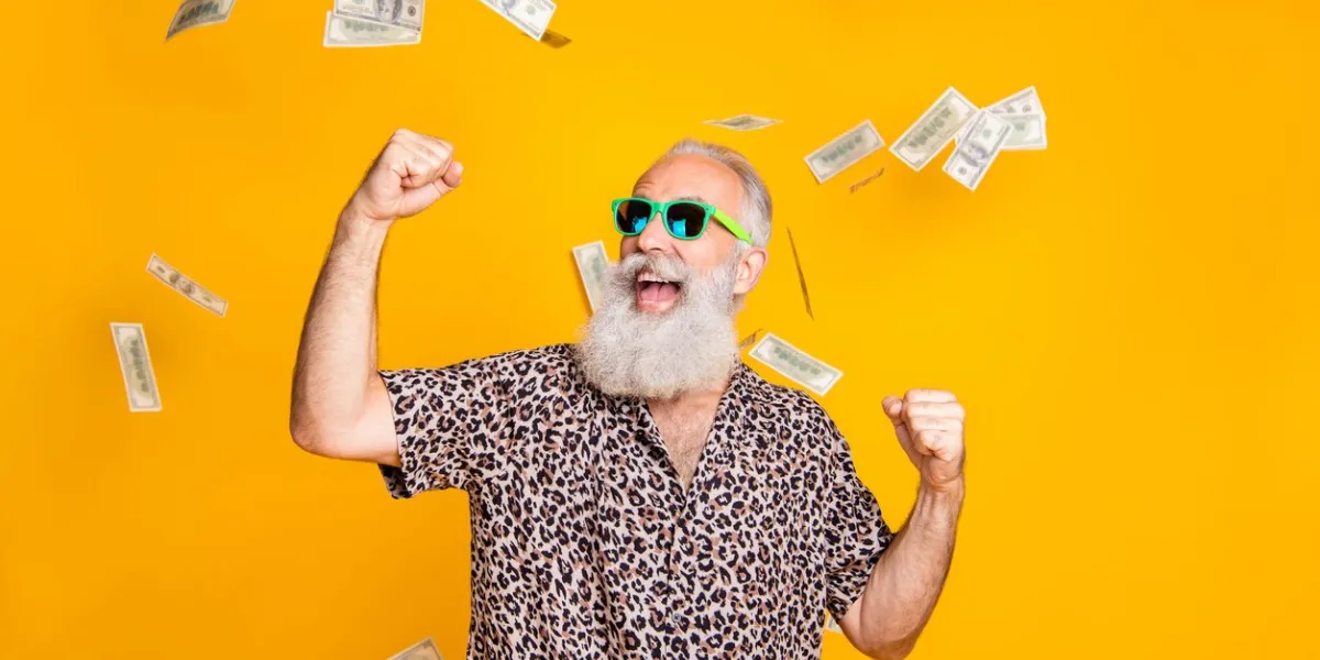 portrait of crazy retired funky bearded old man with eyeglasses eyewear raise his fists, scream yeah celebrate victory look at money falling wearing leopard shirt isolated over yellow background