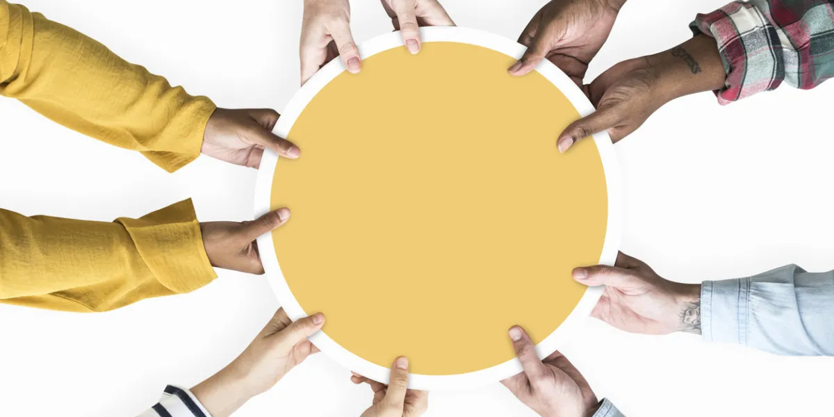 diverse hands supporting a blank yellow round board