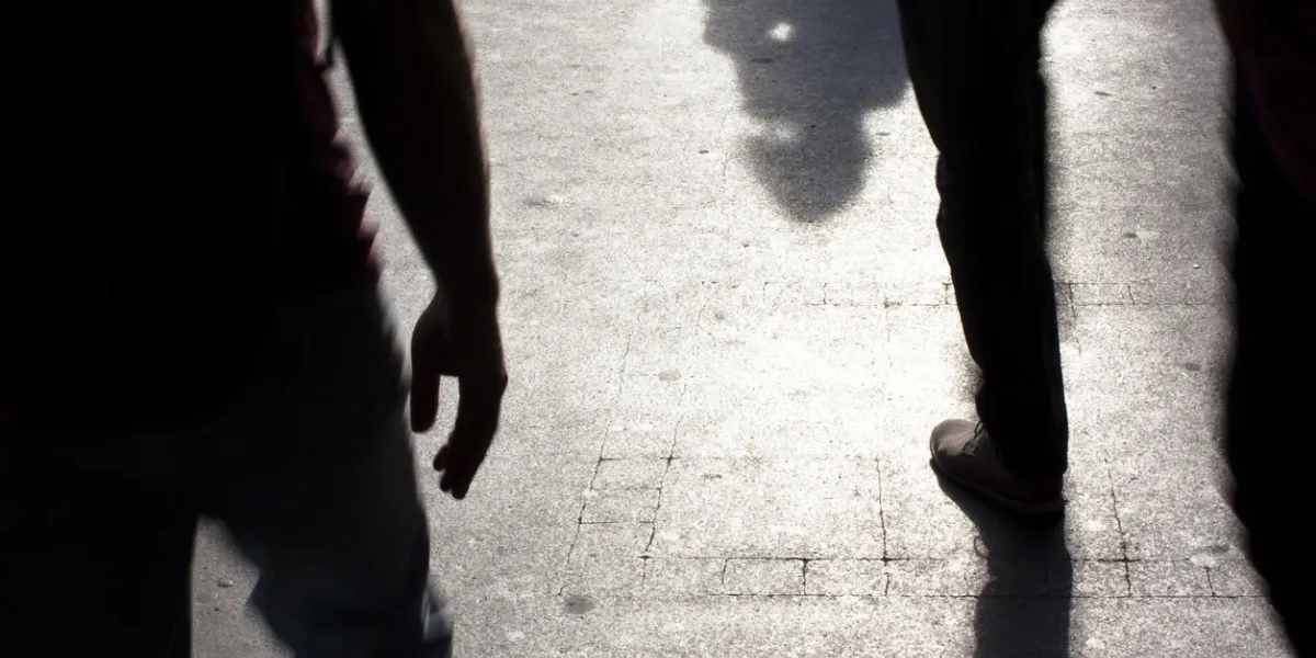 blurry silhouettes and shadows of people walking on the city sidewalk