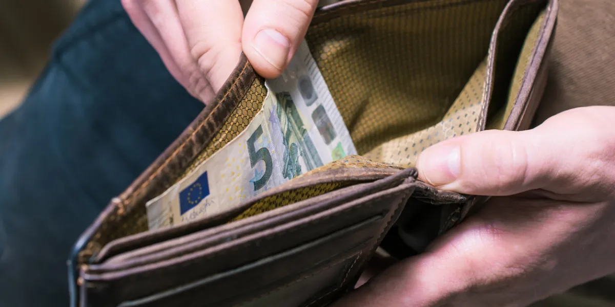 a man showing the last 5 euro in his wallet - poor man concept