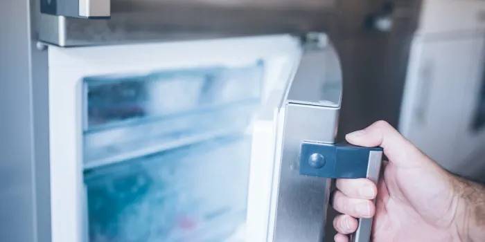 hand of a man opening freezer door in kitchen