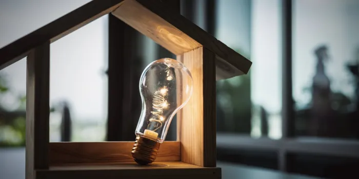 light bulb with wood house on the table, a symbol for construction, creative light bulb idea, power energy or business idea concept ecology, loan, mortgage, property or home