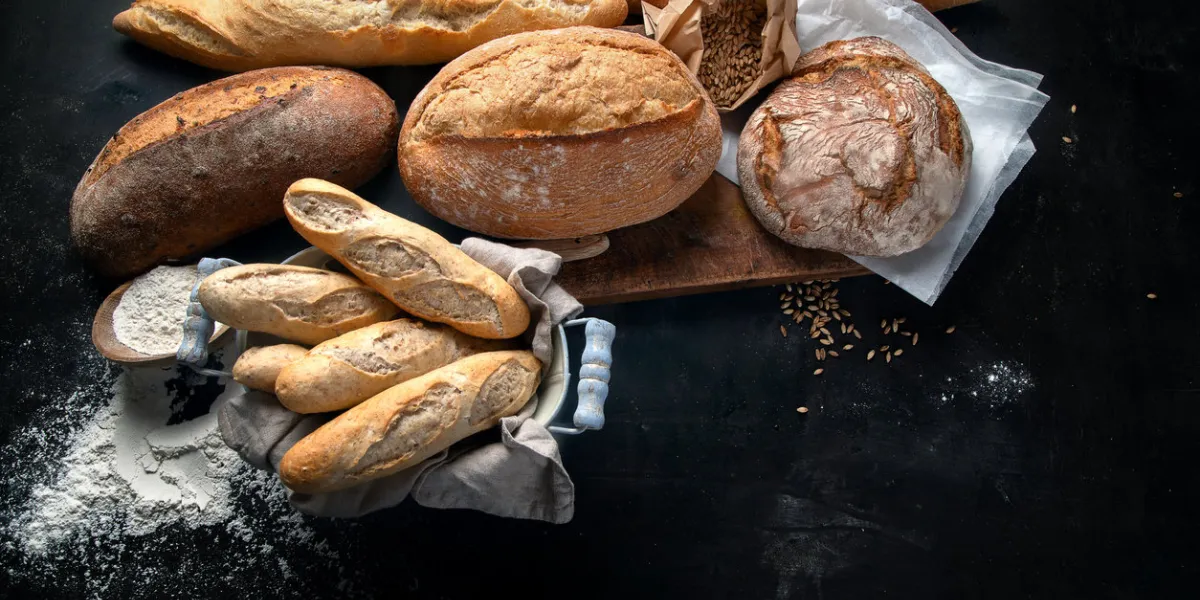 fresh bread and buns on black background with copy space view from above