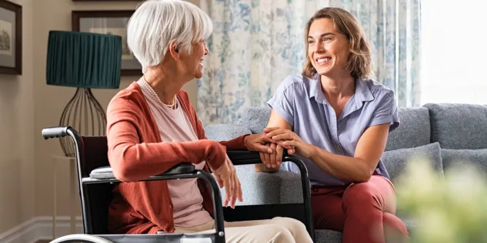 mature woman comforting senior mom sitting on wheelchair at nursing home cheerful woman talking to old disabled mother in wheelchair at elder care centre loving caregiver taking care of elderly woman at home