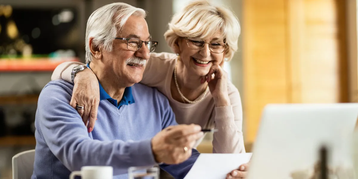 happy senior couple going through home finances and using computer at home