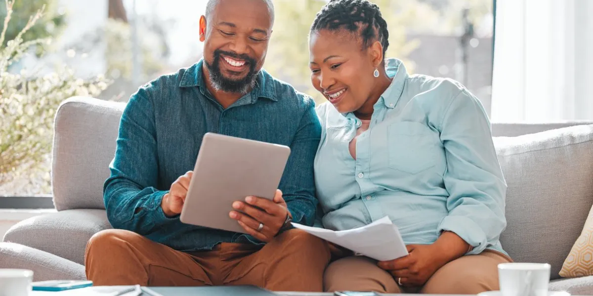 shot of a mature couple looking through their bills while using a digital tablet