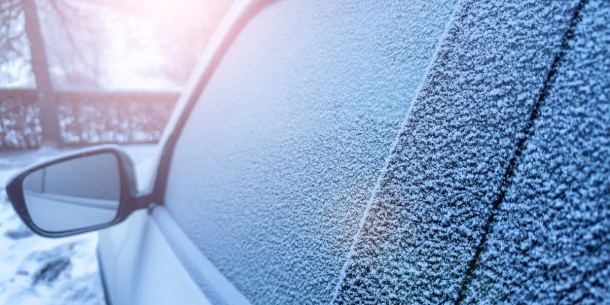 window of the car covered with frost during winter morning and sun flare light reflecting