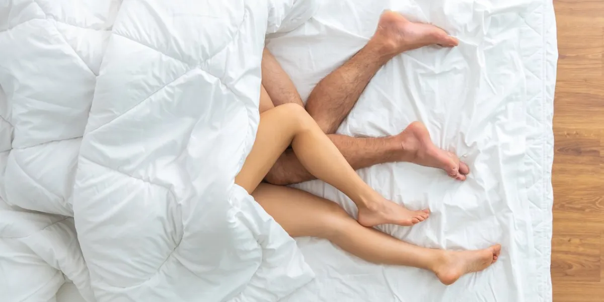 the couple under blanket laying on the bed view from above