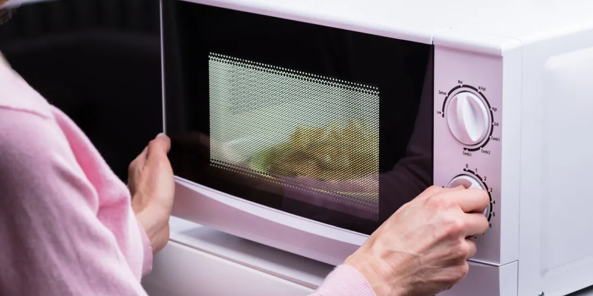 close-up of woman using microwave oven for heating food at home